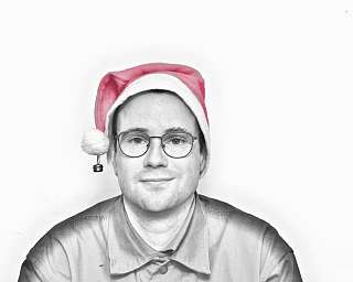 Ein Mann trägt eine rote Weihnachtsmütze und lächelt.