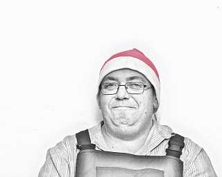 Ein Mann trägt eine Weihnachtsmütze und ein Schürze.