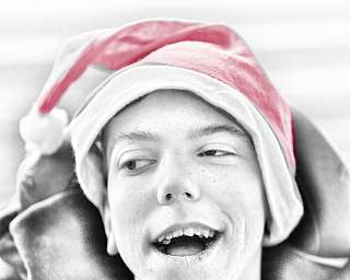 Ein Junge trägt eine rote Weihnachtsmütze und lächelt.