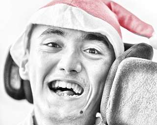 Junge mit Weihnachtsmütze lächelt fröhlich in die Kamera.