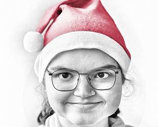 Lächelnde Person trägt eine rote Weihnachtsmütze.