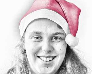 Eine Person mit einer roten Weihnachtsmütze lächelt freundlich.