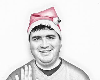 Lächelnder Mann in Weihnachtsmütze, winkt freundlich.