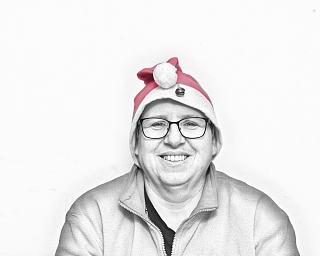 Lächelnde Person trägt eine rote Weihnachtsmütze vor weißem Hintergrund.