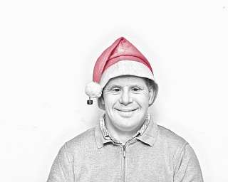 Lächelnder Mann trägt eine rote Weihnachtsmütze vor weißem Hintergrund.